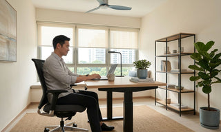 Man working at a wooden standing desk with mesh office chair in a bright Singapore home office.