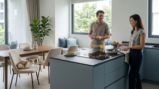 Couple using a built-in induction hob in a modern Singapore open kitchen with dining area and cat nearby