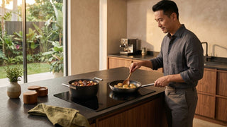 Man using induction stove cookware on a sleek black hob in a warm modern kitchen