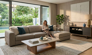 Landed home living room in Singapore with large beige sectional sofa, coffee table, TV console, rug, and garden view.