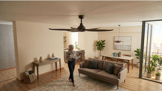 Large dark ceiling fan in a bright Singapore living and dining room with sofa, balcony plants and warm wood flooring