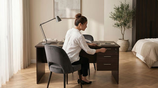 Long study table with drawer storage in a bedroom workspace, styled with a desk lamp, books, wardrobe, and soft daylight