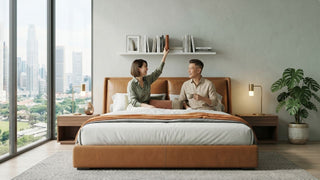 Couple relaxing on a tan floor bed frame in a modern Singapore bedroom with low-profile design, city view, and indoor plant