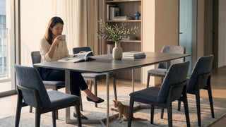 Woman seated at a six-seat sintered stone dining table in a modern Singapore apartment