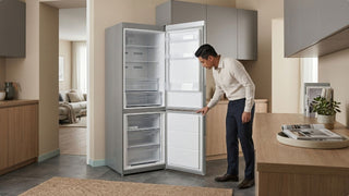 Man checking an open silver refrigerator in a modern Singapore kitchen with wood cabinets and warm neutral styling