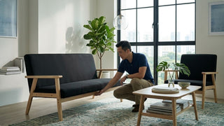 Man inspecting a black wooden sofa in a bright Singapore living room