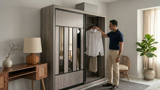 Man hanging a shirt in a grey pole system wardrobe in a modern Singapore bedroom with rattan chair and soft natural light