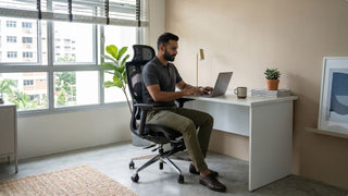 Man working at a white desk with ergonomic chair in a compact Singapore home office