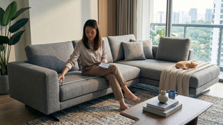 Woman measuring a grey sectional sofa in a Singapore condo living room before delivery planning.