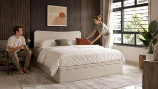Upholstered bed frame in a modern Singapore bedroom with a couple arranging the space