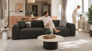 Dark charcoal 3-seater sofa in a modern 4-room HDB living room with a practical layout and warm natural light