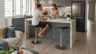Modern black chrome bar stools at a Singapore kitchen island with a couple preparing snacks in a compact home