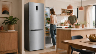 Silver bottom-freezer refrigerator in a warm modern Singapore kitchen with fresh groceries and a practical family dining layout.