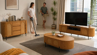 Wooden living room furniture set in a modern Singapore home with a couple tidying before vacuuming