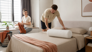 Cream booster pillow on a neatly made bed in a modern Singapore bedroom during a relaxed home tidying moment.