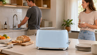 Pale blue bread toaster on a modern Singapore kitchen island with breakfast bread and a couple preparing the morning routine