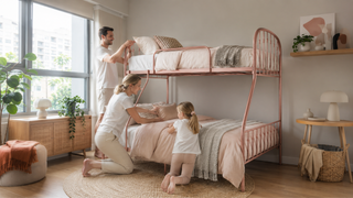 Rose metal bunk bed in a bright Singapore apartment bedroom with a family arranging soft bedding.