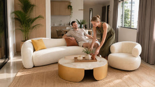 White curved couch set in a bright Singapore living room with a couple arranging the space for everyday comfort.