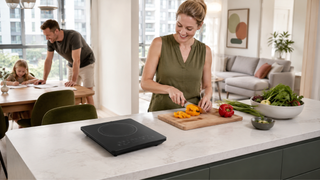 Portable electric induction cooktop on a kitchen island in a bright modern Singapore family home