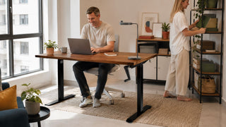 Ergonomic height-adjustable desk in a bright Singapore home office with a couple using the workspace.