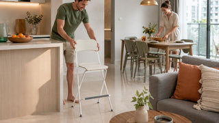 White foldable bar stool used as flexible extra seating in a modern Singapore kitchen and dining area.