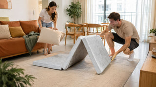 Foldable mattress being set up in a modern Singapore living room for a practical guest sleeping space