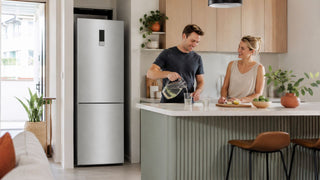 Tall silver fridge with ice maker in a modern Singapore kitchen-dining area with a couple preparing chilled drinks