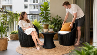 Black rattan garden chair set on a plant-filled balcony in a modern Singapore home