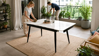 White marble-look garden table in a modern Singapore balcony dining area with a couple preparing the space for guests.