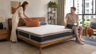 Hybrid mattress in a modern Singapore bedroom with a couple arranging pillows in a practical HDB-style home