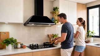 Black kitchen chimney hood above a gas hob in a bright modern Singapore home kitchen with a couple cooking together.