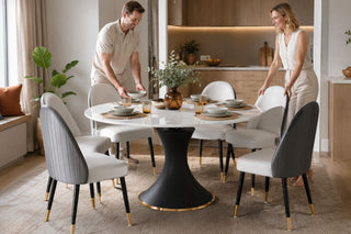Round marble-look luxury dining table set in a bright modern Singapore condo dining area with a couple preparing the table for guests.
