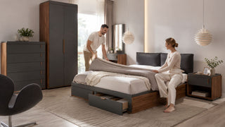 Couple arranging bedding on a modern storage bed in a practical Singapore condo bedroom.