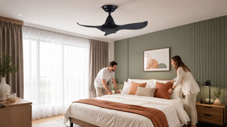 Black master bedroom ceiling fan above a modern Singapore bedroom with a couple arranging the bed
