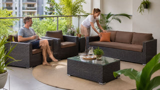 Outdoor sofa set on a Singapore balcony with a couple arranging cushions for a practical outdoor seating area