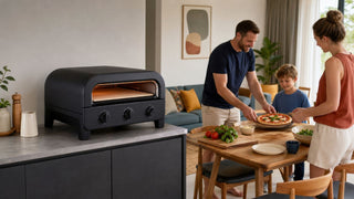 Matte black pizza oven in a modern Singapore kitchen-dining home with a family preparing a simple meal.