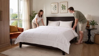 White quilted queen bed frame in a bright Singapore bedroom as a couple arranges the bedding