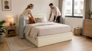Cream upholstered queen bed in a modern Singapore bedroom with a couple arranging bedding for a practical home setup