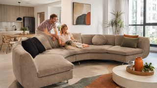 Round beige sectional sofa in a modern Singapore condo living room with a relaxed couple and warm neutral decor.