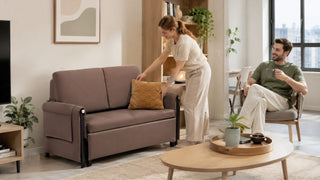 White couple arranging a compact sofa bed in a bright modern Singapore condo living room for practical guest seating.