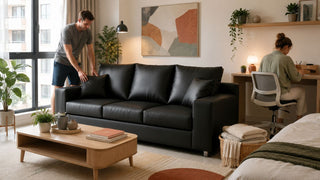 Black three-seater sofa in a compact Singapore home with a study desk and bedding setup for shared study and sleep use.