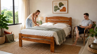 Solid wood bed in a bright modern Singapore bedroom with a couple arranging the space.
