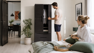 Dark charcoal storage cabinet in a bright Singapore bedroom with a couple organizing clothes and bedding.