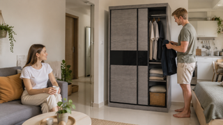 Grey sliding wardrobe in a compact Singapore studio apartment with a couple organizing clothes and keeping clear walking space.