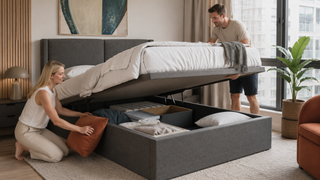 White couple organizing a grey tatami storage bed in a modern Singapore condo bedroom with practical under-bed storage.