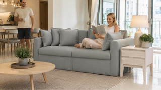 Grey three-seater fabric sofa in a bright Singapore condo living room with a relaxed couple enjoying a quiet home moment.