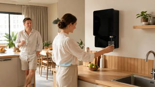 Modern black wall-mounted water filter in a bright Singapore kitchen with a couple using filtered water at home
