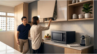 Couple checking kitchen storage above a countertop microwave oven in a modern HDB-style kitchen in Singapore