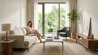 Minimalist Singapore living room with a low-profile beige sofa, wooden TV console, coffee table, accent chair, and warm natural light.