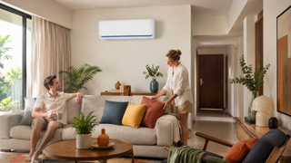 Mitsubishi Electric wall-mounted air conditioner in a modern Singapore living room with a relaxed couple and warm family-friendly styling.